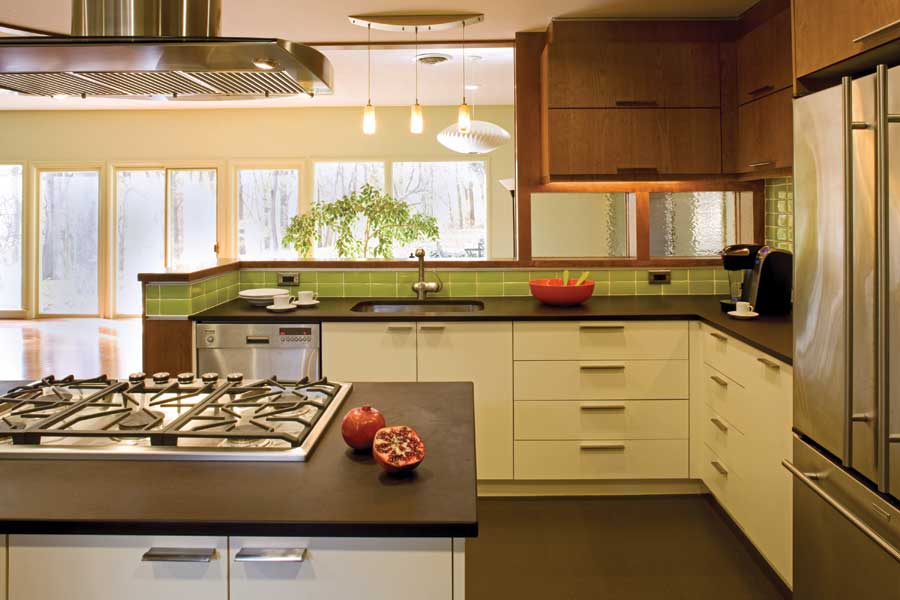 Formerly closed off from the rest of the house, the kitchen now connects with the living room, where natural light streams through floor-to-ceiling windows overlooking the wooded backyard. The kitchen's natural tones mirror the backyard's colors, connecting the indoors to the home's natural environment.